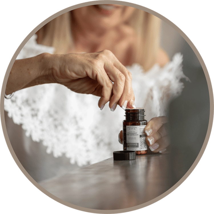Older American Caucasian Woman Wearing A White Blouse Removes Tamper-Evident Seal From The Strongest Cbd Isolate Capsules Product.