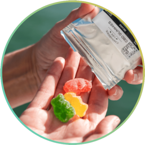 Tres gomitas de CBD en la mano junto a la playa, cada gominola ofrece 25 mg de cannabidiol.